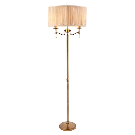 Interiors 1900 Ambledale two-light floor lamp in antique brass with twin candle fittings and a champagne pleated fabric drum shade on a round base.
