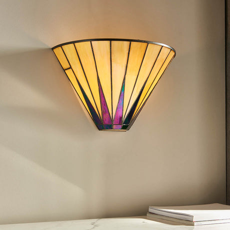 Wistcombe Tiffany wall light with a fan-shaped leaded glass shade in cream and multicoloured tones, mounted above a marble surface with books.