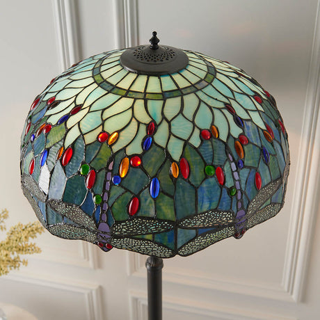 Alderworth Tiffany floor lamp shade in blue leaded glass with dragonfly motif, coloured jewel accents and dark metal finial on a slim column base.
