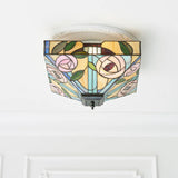 Tiffany Thornmere Medium 2 Light flush ceiling light with square multicoloured leaded glass shade featuring pink roses and green leaves, on a white ceiling.