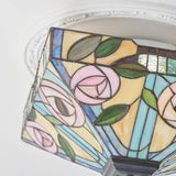 Close-up of the Tiffany Thornmere Medium 2 Light flush ceiling light, showing leaded stained glass panels with pink roses, green leaves and blue accents.