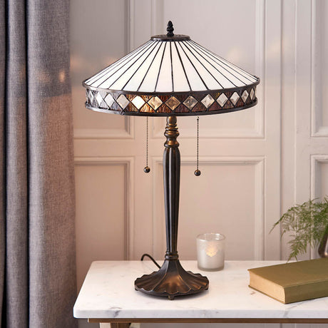Brindleigh medium Tiffany table lamp with a conical leaded glass shade in white with diamond border, on a dark metal base atop a marble console.