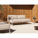 Sit Aluminium 2 Seater Garden Sofa with beige cushions and white powder-coated sled-leg frame, shown on a gravel patio against a wooden slat wall.