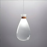 The Soffi Small Glass Pendant Light - Clear showcases a modern design with its sleek, teardrop-shaped shade and handcrafted elegance. Hanging from the ceiling, it emits a soft glow and features a metallic accent near the top against its simple gray backdrop, epitomizing minimalist lighting at its best.
