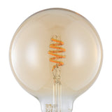 Close-up of a smart amber glass G125 globe bulb with a spiral LED filament and E27 brass-coloured screw base, shown against a white background.