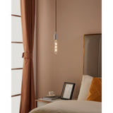 Pendant light with clear tubular LED bulb, E27 fitting, crossed filament design, warm white glow, shown above a bedside table in a bedroom setting.
