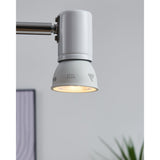 Smart Colour Changing LED Bulb GU10 fitted in a white spotlight on an adjustable wall-mounted arm, shown illuminated in a light grey room setting.