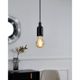 Pendant light with a Smart LED GLS Bulb E27 A60 7W CCT, amber glass globe and spiral filament, shown glowing in a black fitting above a light grey room setting.