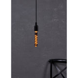 Smoked LED tubular bulb E27 with glowing amber spiral filament, hanging from a black pendant fitting against a dark textured wall.
