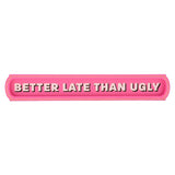 Pink wooden wall plaque with rounded ends and gold trim, reading "BETTER LATE THAN UGLY" in pale pink capitals with dark shadow lettering, on a plain white background.