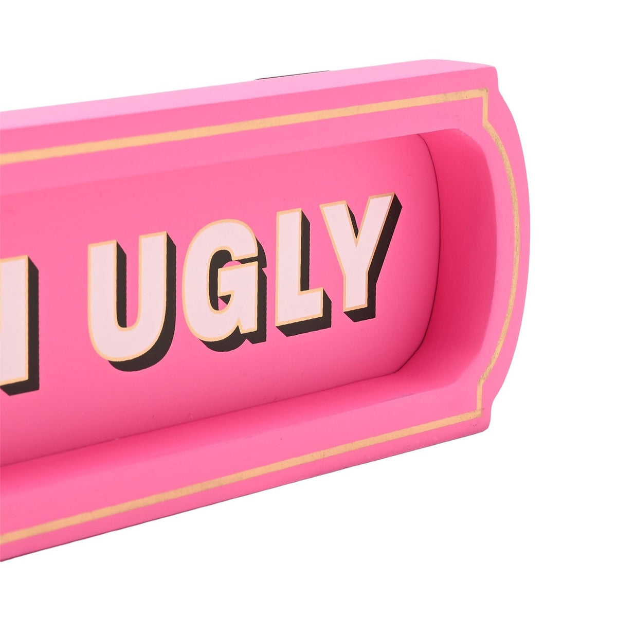 Close-up of the pink wooden "Better Late Than Ugly" wall plaque, showing bold shadowed lettering in a recessed panel with a gold-lined raised border.