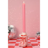 Ceramic Heart Cowboy Boot Taper Candle Holder in pink and white with red bows and hearts, holding a lit pink candle against a pink backdrop with disco balls.