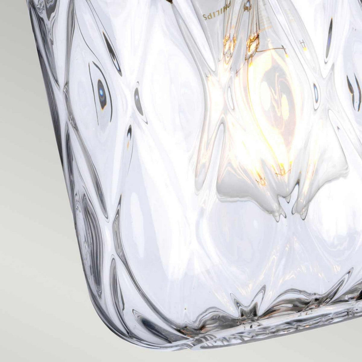 The Sola 1 Light Pendant, with its clear glass encasement adorned in elongated ovals, showcases a delicate dance of light reflections. Its polished nickel accents add a touch of elegance as it hangs against a soft gradient backdrop.