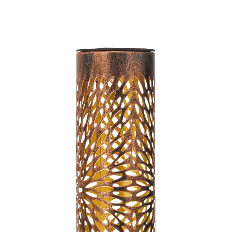 Solar spike light with a slim steel cylinder in weathered bronze, cut in a floral pattern revealing a gold inner surface, topped with a black cap, shown on a plain white background.