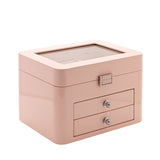 Pink wooden jewellery box with a glass-top lid revealing lined compartments, plus two pull-out drawers with round knobs, shown on a plain white background.