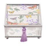 Square glass trinket box with silver-tone frame, clear glass sides, butterfly and purple floral lid design, and a purple tassel pull, shown on a white background.
