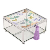 Square glass trinket box with silver-tone frame, lid featuring butterflies among leaves and purple florals, clear sides and a purple tassel on the front clasp.