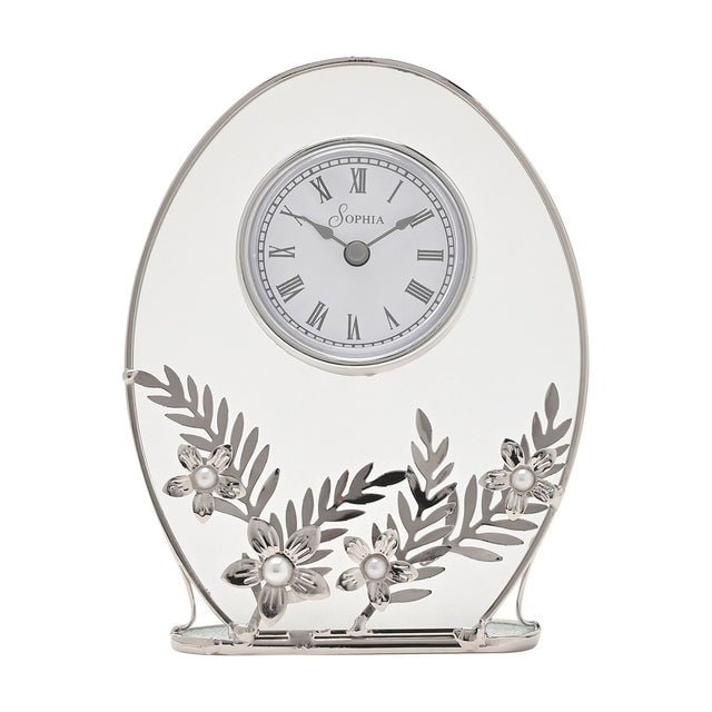 Oval mantel clock with clear glass panel and silver frame, white Roman numeral dial, and silver leaf and daisy details with pearl-effect centres, on a white background.