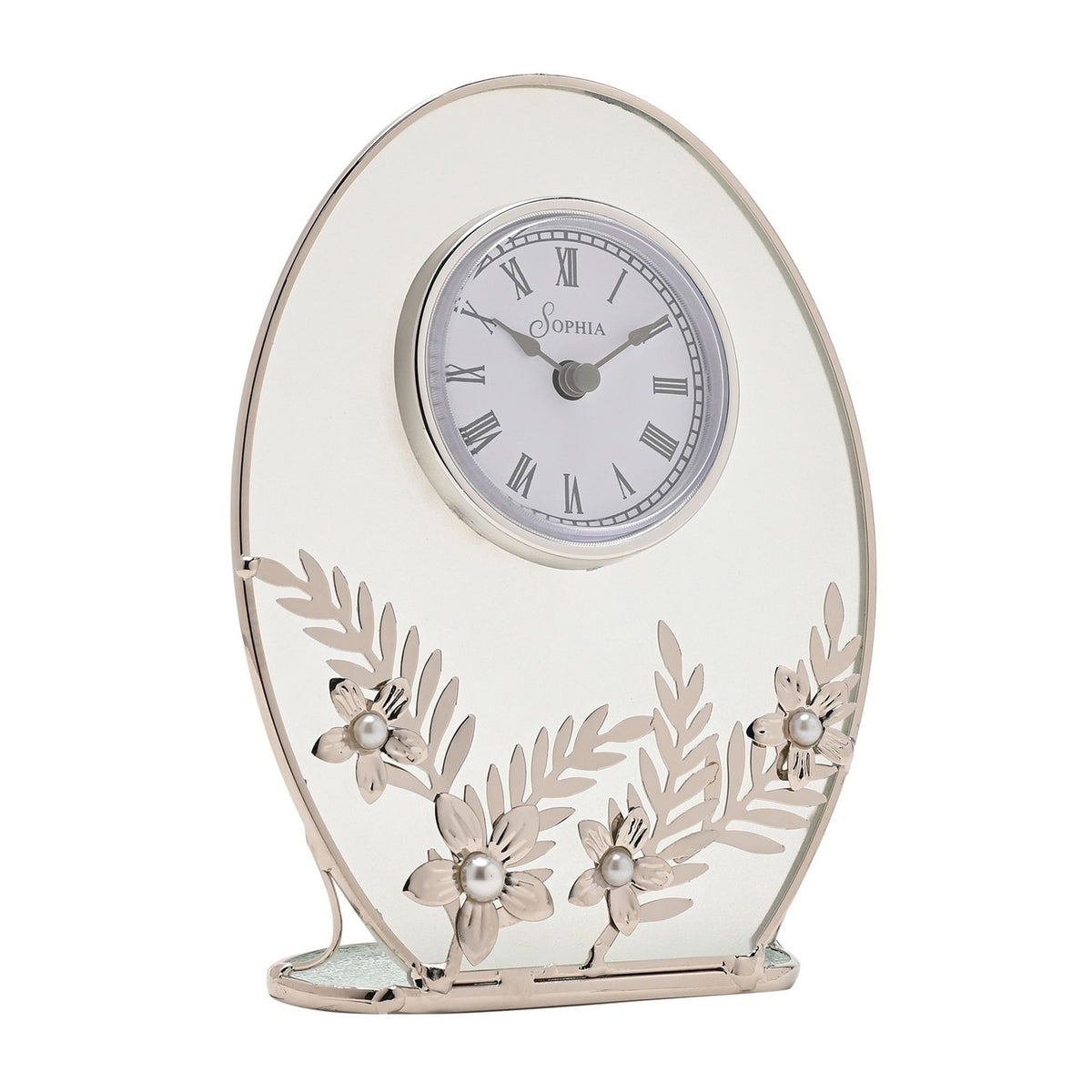 Oval mantel clock with a clear glass panel and silver frame, white Roman numeral dial, and silver leaf sprays with pearl-centred daisies across the base, on a plain white background.