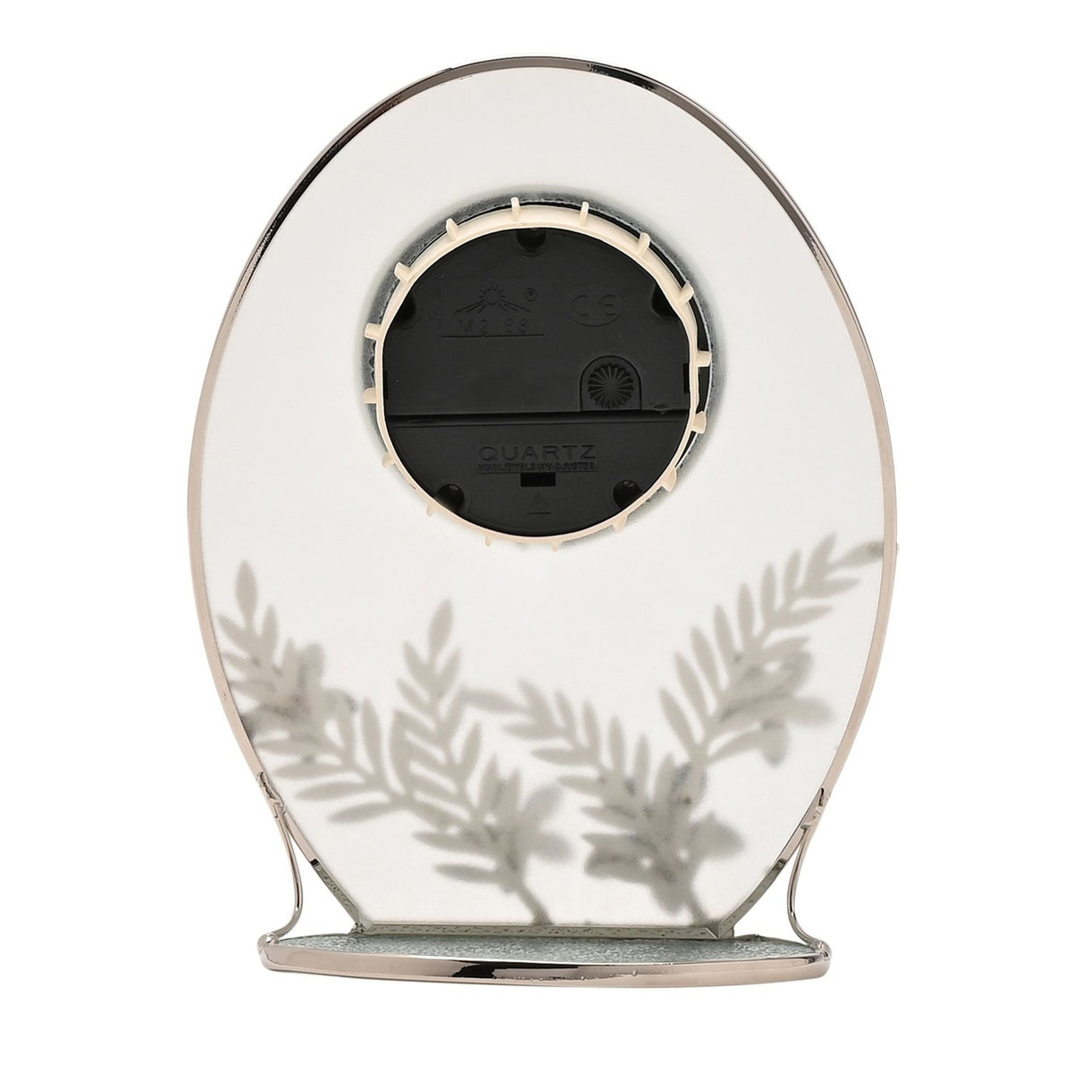 Rear view of the oval mantel clock showing the quartz clock mechanism and silver fern leaf motif etched on the clear glass, set on plain white background.