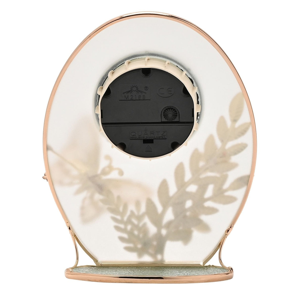 Rear view of the oval mantel clock showing the black quartz movement mechanism, gold-toned frame edges, and frosted glass with faint leaf and butterfly outlines visible through the back.