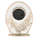 Rear view of the oval mantel clock showing the black quartz movement mechanism, gold-toned frame edges, and frosted glass with faint leaf and butterfly outlines visible through the back.