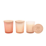 Set of three round frosted glass scented candles labelled Flow, Breathe and Balance in pink, peach and off white, each topped with a wooden lid, on a plain white background.