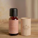 Flow Lotus Wood Block Diffuser with an amber glass oil bottle labelled "Serenity Flow," the natural wood cylinder engraved with a lotus motif, set on a wooden surface.