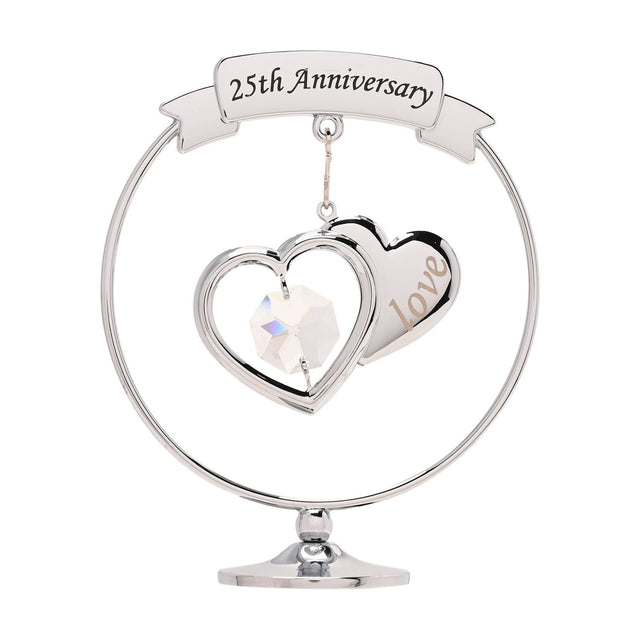 Chrome circle decoration on a round pedestal base, featuring a "25th Anniversary" ribbon banner above two overlapping silver hearts with a clear crystal drop, set against a plain white background.