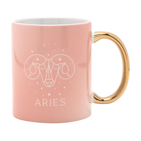Pink stoneware mug with gold handle, featuring a white line-drawn Aries ram's head and stars above "ARIES" text, shown on a plain white background.