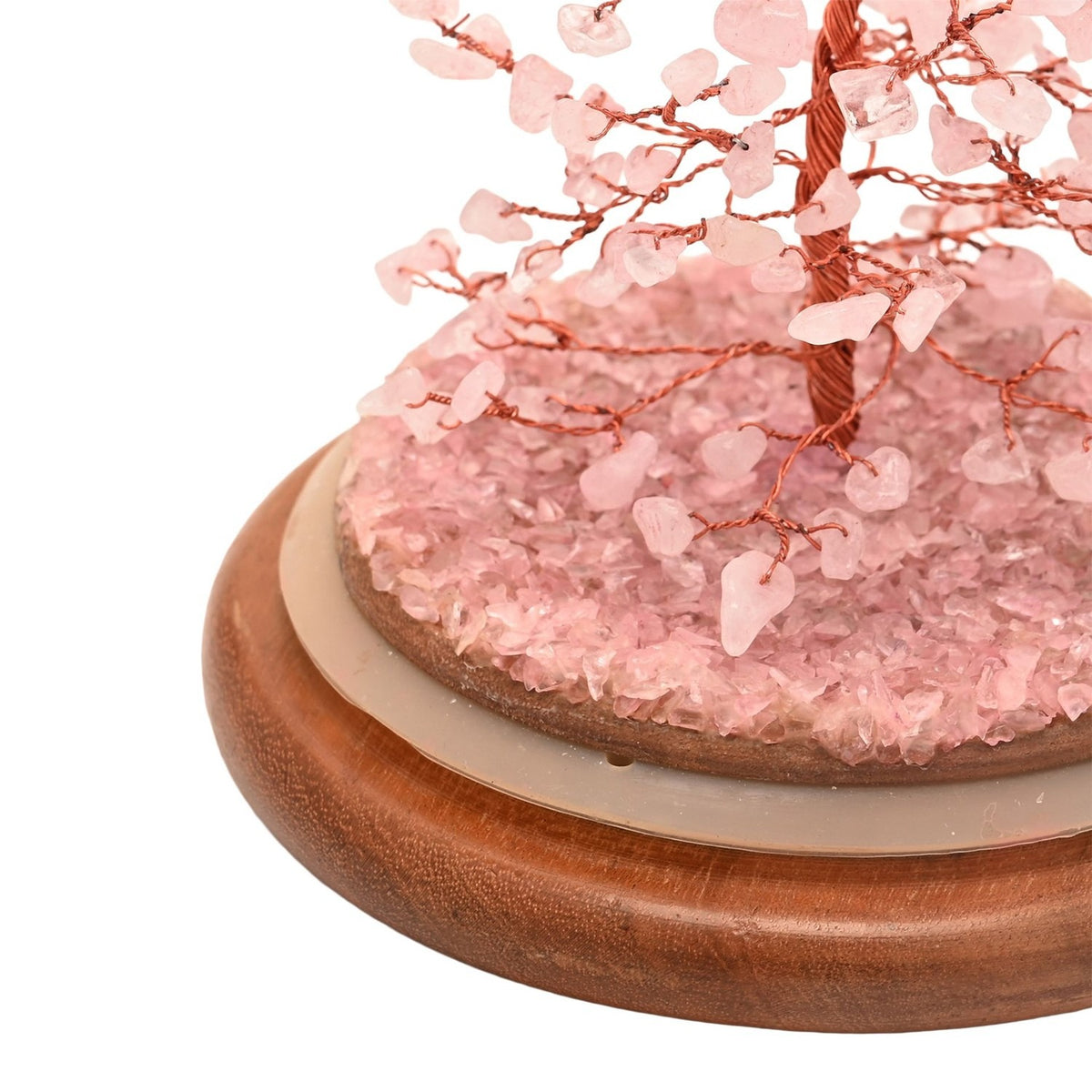 Close-up of the Gemstone Dome Tree figurine's base, showing a copper wire trunk with pink gemstone chips scattered on a round wooden stand, set against a plain white background.