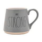 Grey tapered earthenware mug with "BE STRONG" in black lettering, white interior, and a pale unglazed band at the base, shown on a plain white background.