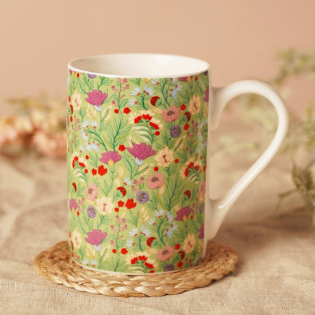 Floral Print Porcelain Mug 10oz in green with cream handle, rim and interior, shown on a woven coaster against a soft pink background.