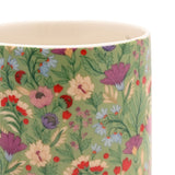 Close-up of a 10oz porcelain mug in green with a floral print of pink, purple, red and cream blooms and pale blue daisies, cream rim and interior.