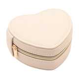 Heart-shaped jewellery box in cream pebble-grain plastic with a gold-tone zip closure, shown on a plain white background.