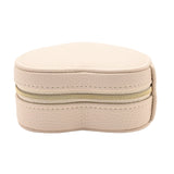 Heart-shaped jewellery box in cream pebble-grain plastic with a gold-tone zip closure, shown against a plain white background.