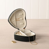 Open heart-shaped jewellery box in black pebbled plastic with cream interior, ring rolls, chain holder and zip divider, shown with rings and necklaces on a wooden surface.