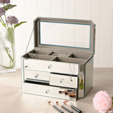 Rectangular 4 drawer mirror glass jewellery box in silver, open lid revealing a mirrored interior tray, with faceted knobs on each drawer, shown on a dressing table.