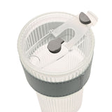 Close-up of a ribbed cold drink tumbler's clear lid with flip-up spout, slide lock and straw opening, grey accents, set on a grey sleeve over the fluted clear body.