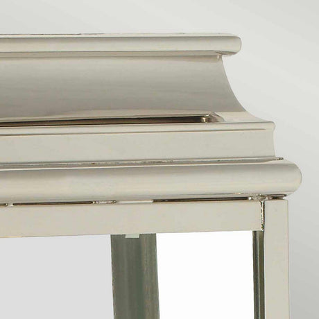 Close-up of a metallic silver corner resembling the St Martins 1 Light Outdoor Wall Light in polished nickel. The top section is curved, giving it a classic and elegant look, and the mirror reflects a soft, neutral background.