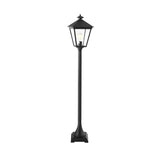 The Turin 1 Light Pillar - Black is a tall, outdoor lamp post featuring a classic lantern design. It is crafted from die-cast aluminum with clear glass panels that reveal a visible light bulb inside. Positioned on a square base, this lamp is perfect for enhancing outdoor landscapes against a plain white background.