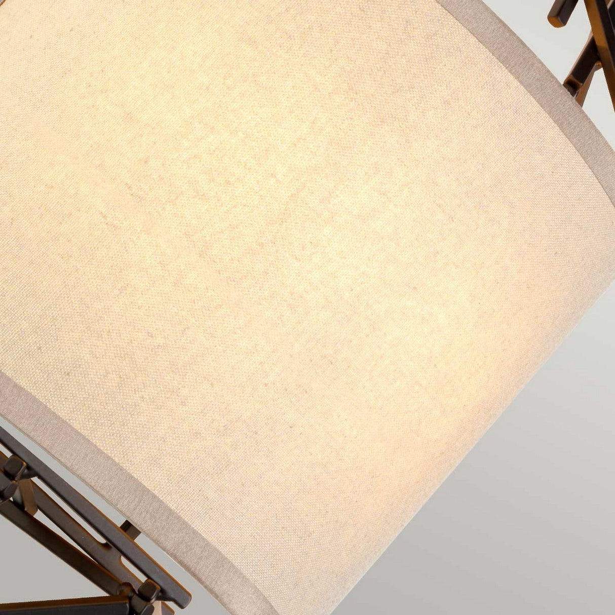 Close-up of a beige fabric lampshade with visible texture, attached to the Taiko 2 Light Wall Light's Olde Bronze metal frame. The image depicts warm light highlighting the shade's woven material against a neutral background, perfectly capturing the essence of decorative lighting that this fixture represents.