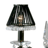 A close-up of the Tara 2 Light Crystal Table Lamp in black chrome without shades, featuring a wire frame and a row of clear crystal-like beads around the base. A faceted crystal ornament on the right enhances its sparkling accents.