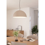 Tarvena Pendant Light with a wide sand-coloured steel dome shade and cream interior, hung on a black cable above a wooden dining table in a neutral-toned room.