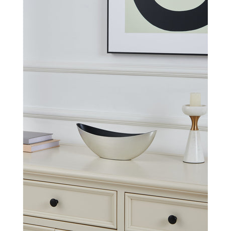Tazeyol Planter 11cm in brushed silver with a black interior, its boat-shaped oval body pointed at both ends, shown on a cream sideboard beside books and a candle holder.