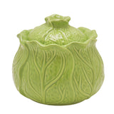 Green glazed stoneware storage jar shaped like a cabbage, with veined, overlapping leaf details and a domed lid topped by a stalk knob, set against a plain white background.