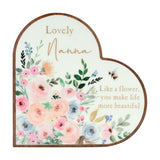 Wooden heart-shaped mantel plaque in white with pastel pink, peach and blue florals, "Lovely Nanna" text and a bee detail, shown on a plain background.