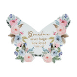 White wooden butterfly-shaped mantel decoration with pink and blue watercolour florals, gold "Grandma never forget how loved you are" text, glossy finish, on a plain background.