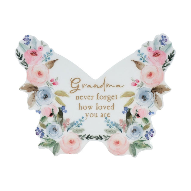 White wooden butterfly-shaped mantel decoration with pink and blue watercolour florals, gold "Grandma never forget how loved you are" text, glossy finish, on a plain background.