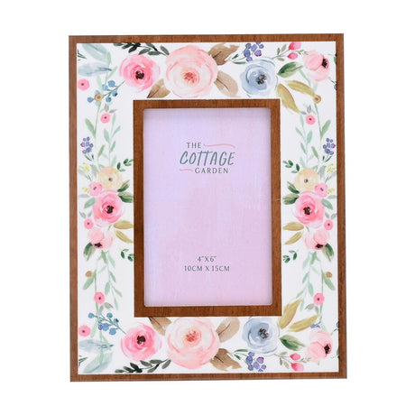 Rectangular wooden photo frame with white face featuring watercolour-style pink, peach, blue and green floral border, raised wood-tone inner frame holding a 4x6in photo, on a plain white background.